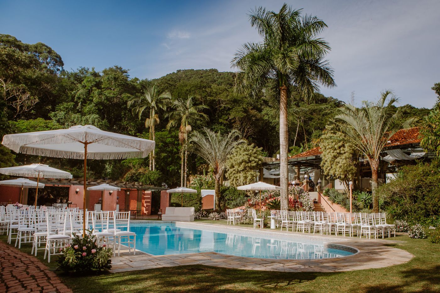 Jardim com piscina, palmeiras e ombrelones
