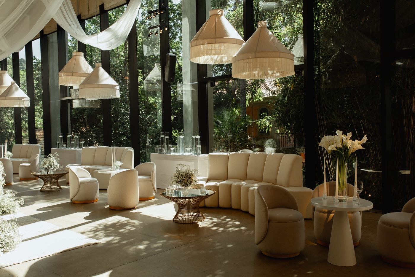 Lounge com sofás brancos e luminárias de palha no salão