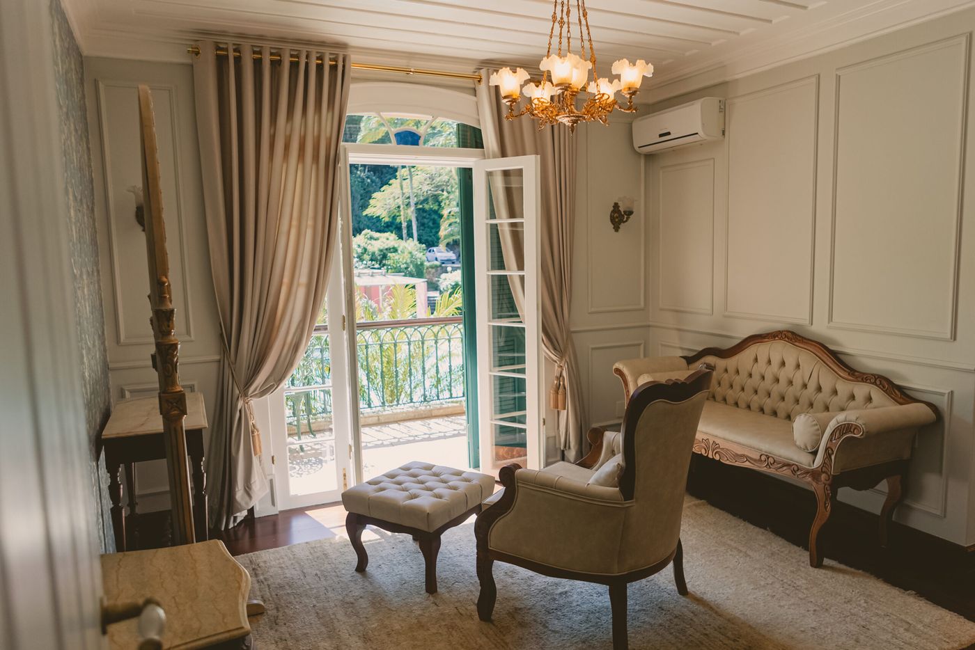 Suíte da noiva com poltronas, lustre e janelas para o jardim