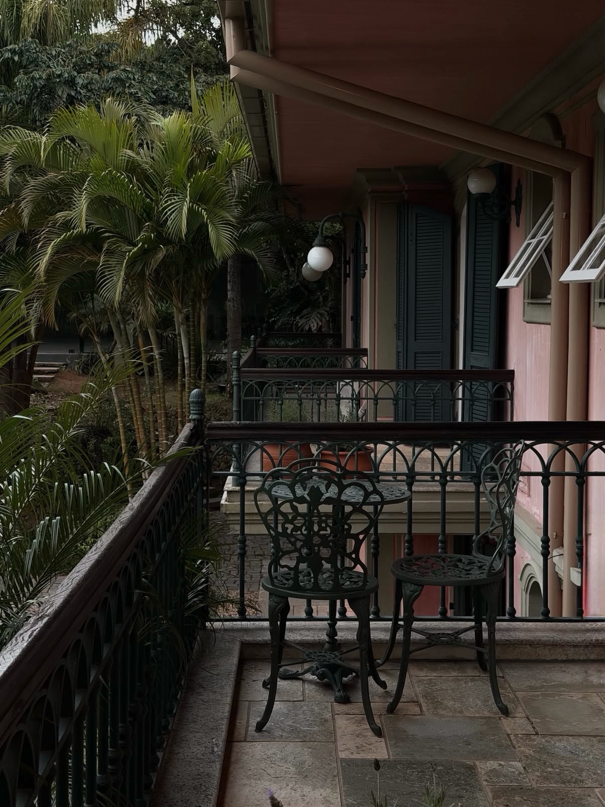 Varanda do casarão com mesa de ferro e jardim